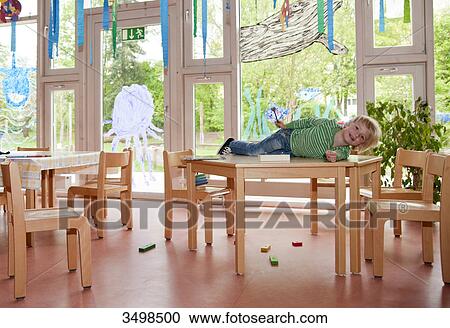 Young boy lying on a table in a kindergarten View Large Photo Image Stock Image - Young boy lying on a table in a kindergarten . Fotosearch