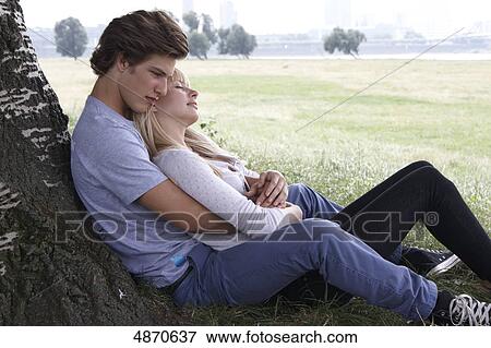 Young couple embracing at tree trunk View Large Photo Image Stock Photo - Young couple embracing at tree trunk . Fotosearch
