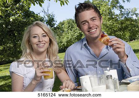 Picture - Young couple having breakfast in park . Fotosearch