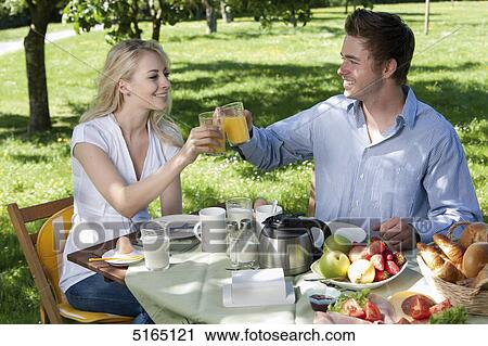 Stock Image - Young couple having breakfast in park . Fotosearch