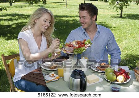 Stock Image - Young couple having breakfast in park . Fotosearch