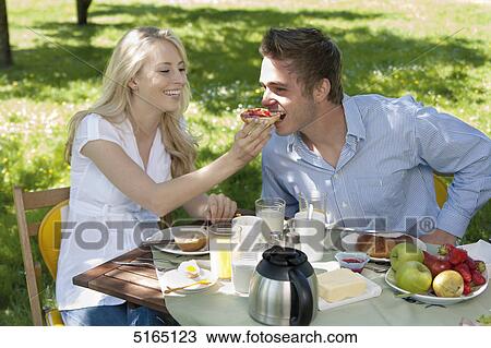 Stock Image - Young couple having breakfast in park . Fotosearch