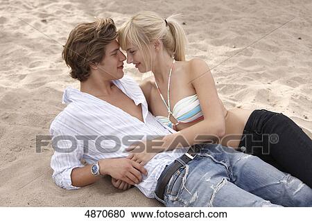 Young couple in sand smiling at each other View Large Photo Image Stock Image - Young couple in sand smiling at each other . Fotosearch