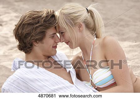 Young couple in sand smiling at each other View Large Photo Image Stock Image - Young couple in sand smiling at each other . Fotosearch