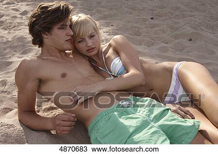 Stock Image - Young couple in swimwear lying in sand . Fotosearch
