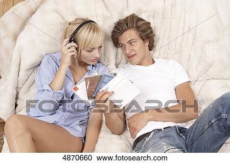 Stock Image - Young couple listening to music in bed . Fotosearch