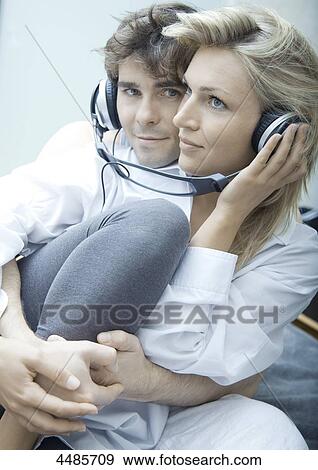 Stock Photo - Young couple listening to music with headphones . Fotosearch
