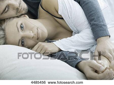 Young couple lying hand in hand in bed View Large Photo Image Stock Photograph - Young couple lying hand in hand in bed . Fotosearch