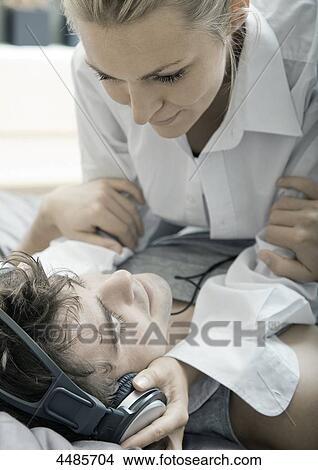 Young couple on bed listening to music with headphones View Large Photo Image Picture - Young couple on bed listening to music with headphones . Fotosearch