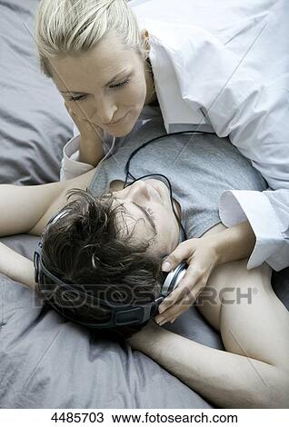 Young couple on bed listening to music with headphones View Large Photo Image Stock Image - Young couple on bed listening to music with headphones . Fotosearch