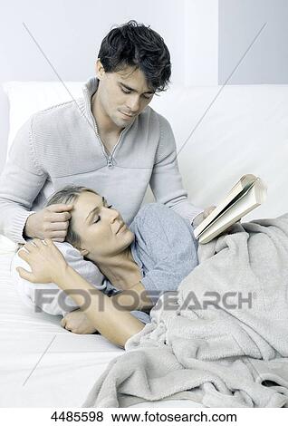 Stock Photo - Young couple on bed reading book . Fotosearch