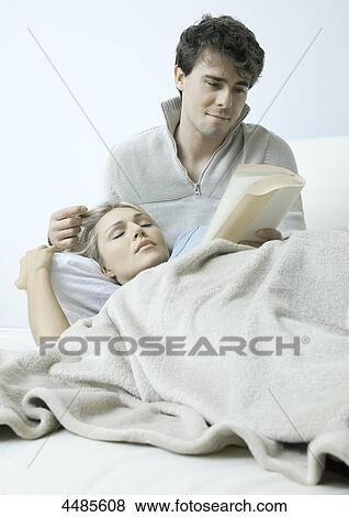 Stock Photo - Young couple on bed reading book . Fotosearch