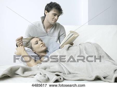 Stock Photo - Young couple on bed reading book . Fotosearch