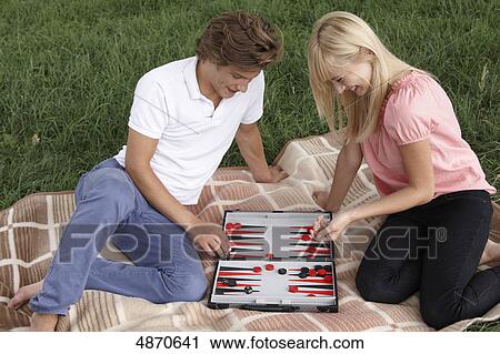 Stock Image - Young couple playing backgammon outdoors . Fotosearch