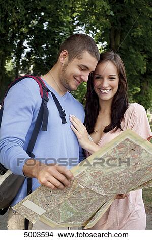 Young couple reading map outdoors View Large Photo Image Picture - Young couple reading map outdoors . Fotosearch