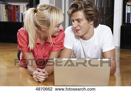 Stock Image - Young couple using laptop on the floor . Fotosearch