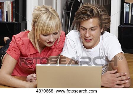 Stock Photo - Young couple using laptop on the floor . Fotosearch
