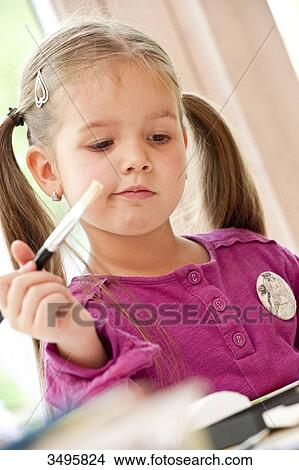 Young girl holding a paint brush, low angle view View Large Photo Image Picture - Young girl holding a paint brush, low angle view . Fotosearch