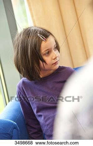 Stock Photo - Young girl sitting on a couch . Fotosearch