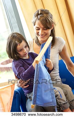 Stock Image - Young girl sitting on the lap of a kindergarten teacher and playing with a toy . Fotosearch