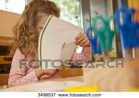 Young girl using scissors to cut paper, low angle view View Large Photo Image Stock Photo - Young girl using scissors to cut paper, low angle view . Fotosearch