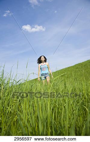 Young girl walking through a rich green meadow, low angle view View Large Photo Image Stock Photo - Young girl walking through a rich green meadow, low angle view . Fotosearch
