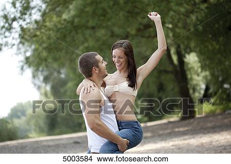 Picture - Young man carrying woman outdoors . Fotosearch