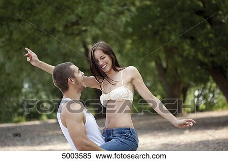 Stock Photography - Young man carrying woman outdoors . Fotosearch