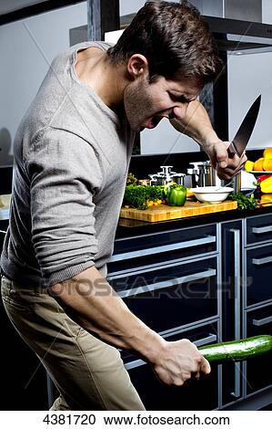 Stock Image - Young man standing angry in kitchen . Fotosearch