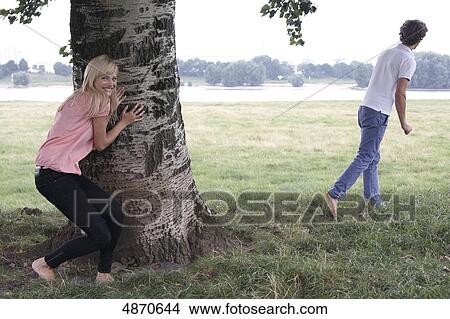 Picture - Young woman and man playing hide and seek . Fotosearch