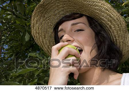 Young woman eating apple from tree, portrait View Large Photo Image Stock Photo - Young woman eating apple from tree, portrait . Fotosearch