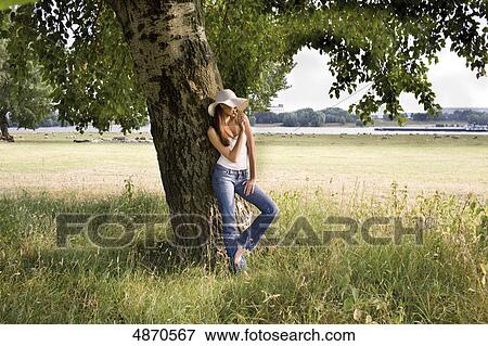 Stock Photo - Young woman eating lolly at tree . Fotosearch