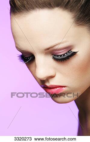 Stock Image - Young woman in front of pink backgound, portrait . Fotosearch