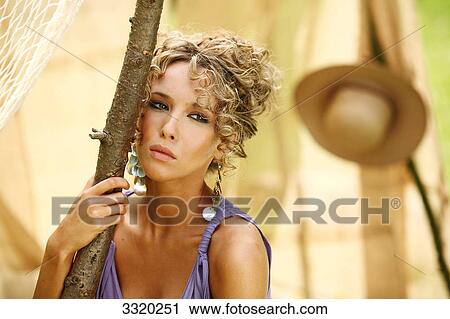 Stock Image - Young woman leaning against a branch, portrait . Fotosearch