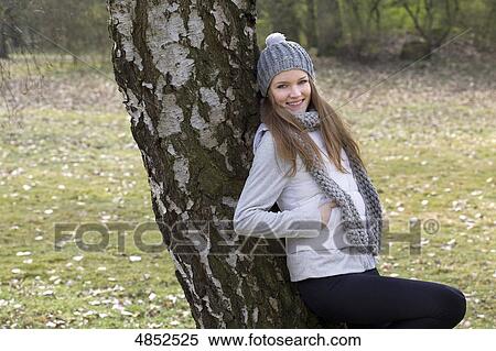 Young woman leaning against tree View Large Photo Image Stock Photography - Young woman leaning against tree . Fotosearch