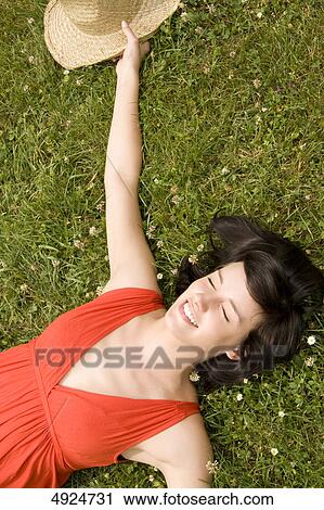 Young woman lying in meadow with eyes closed View Large Photo Image Stock Image - Young woman lying in meadow with eyes closed . Fotosearch