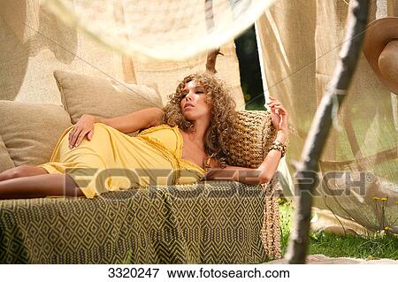 Stock Photo - Young woman lying on a couch in a tent . Fotosearch