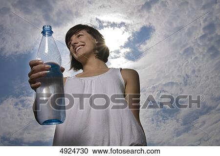 Young woman outdoors holding bottle of water View Large Photo Image Stock Image - Young woman outdoors holding bottle of water . Fotosearch