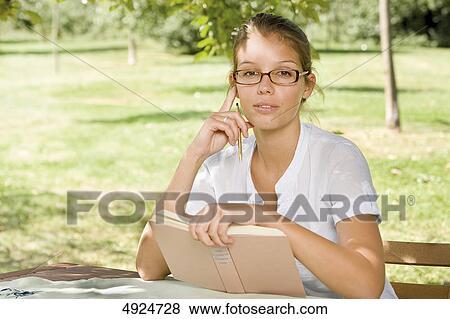 Stock Photo - Young woman reading book outdoors . Fotosearch