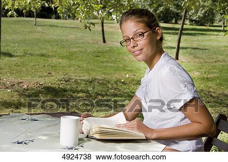 Young woman reading book outdoors View Large Photo Image Stock Photo - Young woman reading book outdoors . Fotosearch