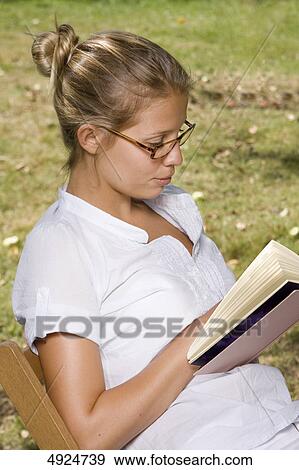 Stock Photo - Young woman reading book outdoors . Fotosearch