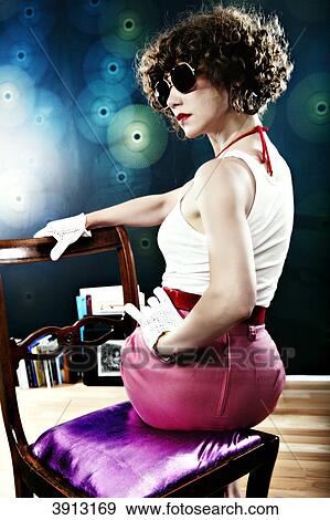 Stock Photo - Young woman sitting on a chair . Fotosearch