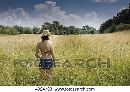 Young woman standing in meadow View Large Photo Image Stock Image - Young woman standing in meadow . Fotosearch