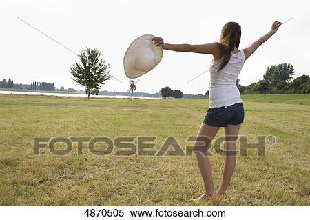 Young woman standing in meadow with arms outstretched View Large Photo Image Stock Photography - Young woman standing in meadow with arms outstretched . Fotosearch