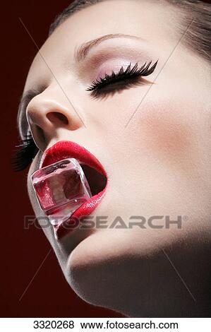 Stock Photo - Young woman with ice cube in her mouth, portrait . Fotosearch