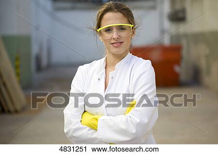 Stock Image - Young woman with lab coat and protective glasses . Fotosearch