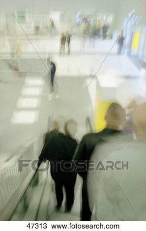Stock Image - Blurred view of people on escalator . Fotosearch