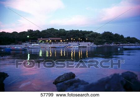 Stock Photo - Boats near a lit up tourist resort, Island of Cres, Croatia . Fotosearch