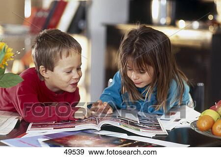 Stock Photo - Boy and his sister looking at travel catalogue . Fotosearch