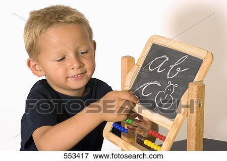 Stock Photo - Boy writing on blackboard with chalk . Fotosearch